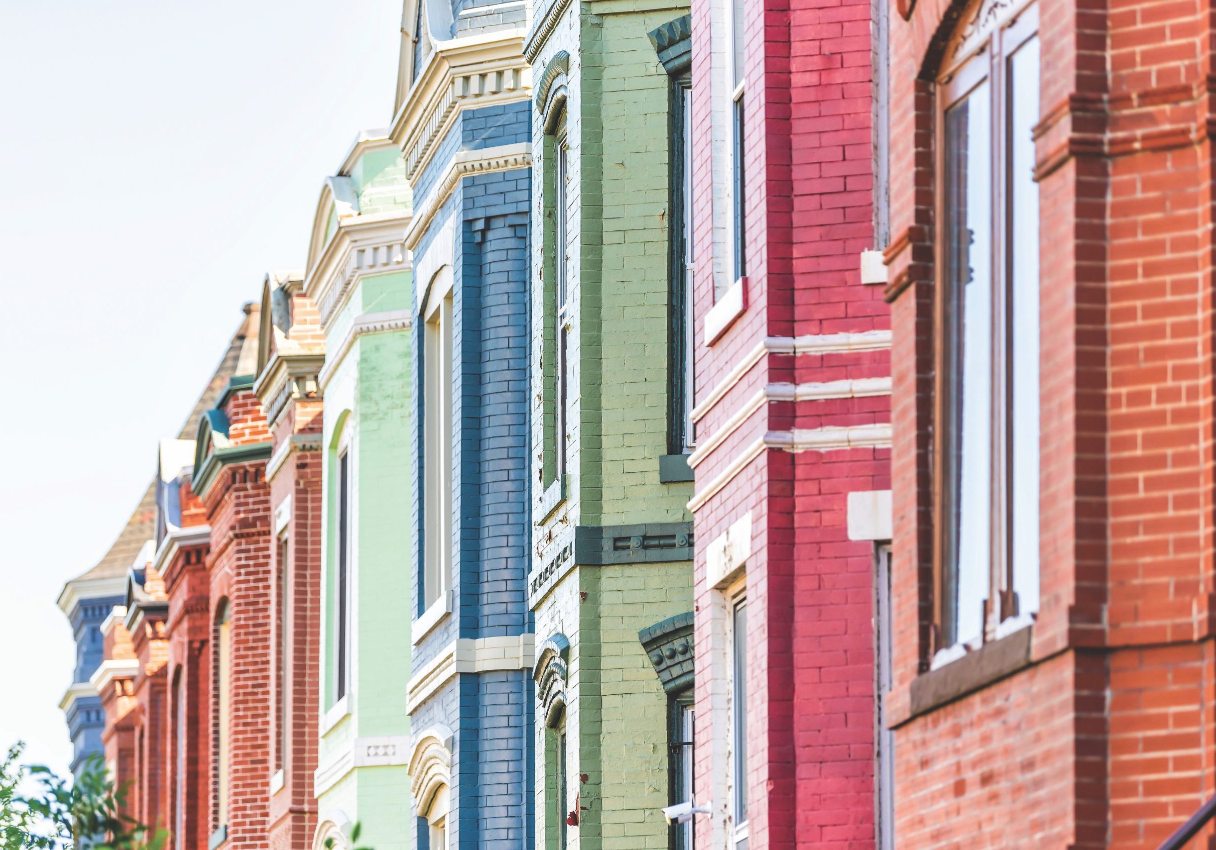 Row of colorful red green and blue painted brick residential townhouses homes houses architecture exterior in Washington DC Capitol Hill neighborhood district
